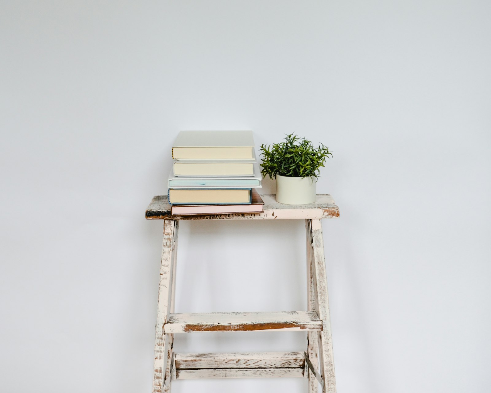 A tidy stack of books resting on a shelf in soft, natural light.
